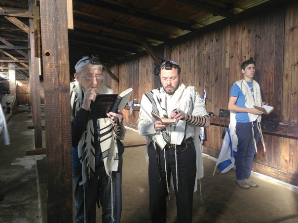 תפילה בצריף שבו שהה מנחם סנדובסקי בבירקנאו. במרכז: יקי מנדלסון, משמאלו מנחם סנדובסקי